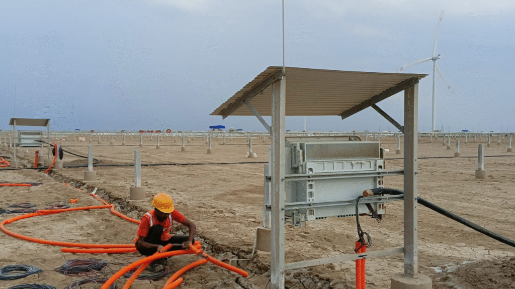 Workers laying electrical cables in a trench at a solar installation site
